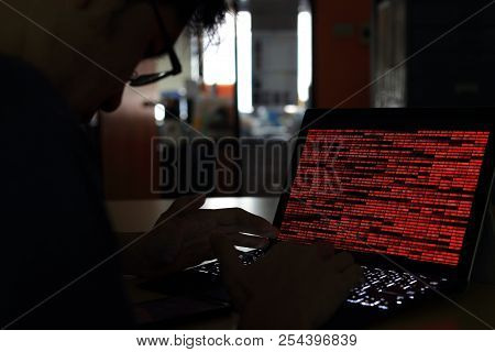 Computer Crime Silhouette Hacker  Typing On Computer In A Dark Room. Working On Binary Code Technolo