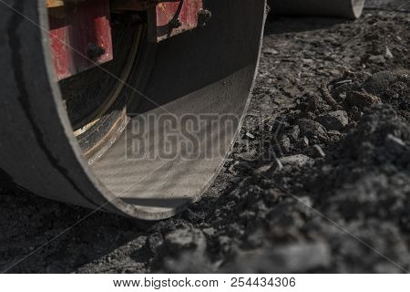 Orange Vibration Roller Compactor Standing On A Ground Near Asphalts Road At Road Construction And R