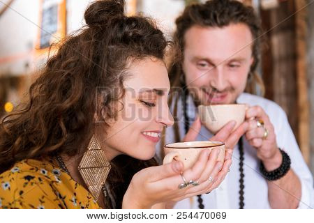 Curly Appealing Woman Smelling Taste Of Nice Tea