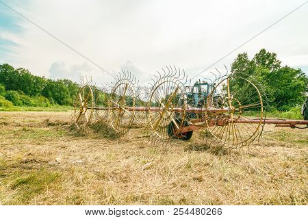 Tedders For Hay In The Meadow In The Background Of The Forest