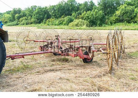 Tedders For Hay In The Meadow In The Background Of The Forest