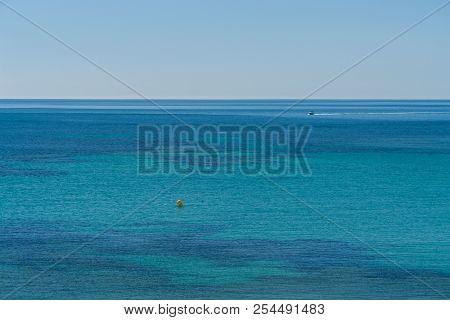 Different Blue Shades At A Beach Of The Mediterranean Sea Aith A Yacht At The Background On A Summer