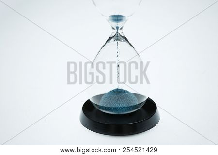 Image of hourglass with blue sand on isolated white background