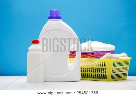 Photo of two bottles of detergents and yellow basket with towels