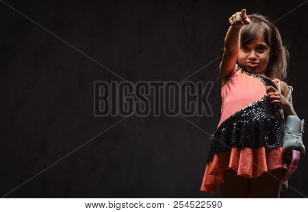 Little Girl Dressed In Skater Dress Holds Ice Skates Scoffs And Points With His Finger. Isolated On 