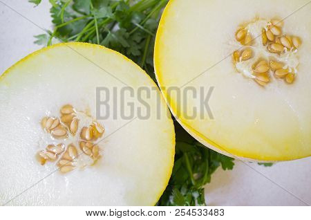 Galia Melon Break In Half Over Parsley Background. Closeup