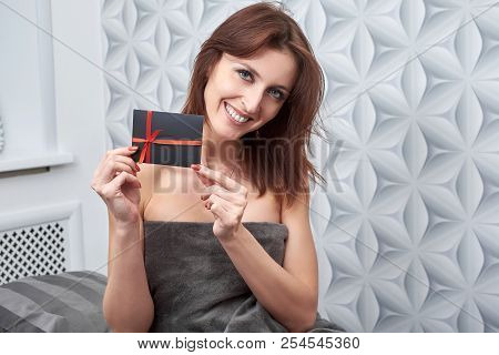 The Client Of The Cosmetology Clinic Shows A Gift Card