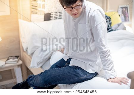 Young Asian Man Sitting On Th Bed Choosing Furniture In Showroom. Home Decaration Buying Concept