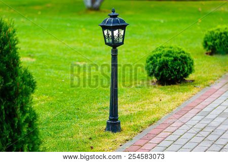 Metal Black Streen Lamp Standing On Green Lawn