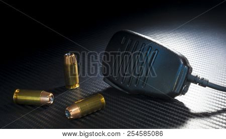 Center Fire Pistol Ammunition And A Microphone On A Dark Bavckground