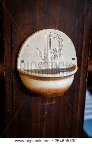 Old Stoup Of Clay With Cross On Dilapidated Wall Of Wood, With Sign Of The Church,