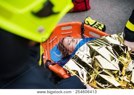 An Injured Woman In A Plastic Stretcher After A Car Accident, Covered By Thermal Blanket.