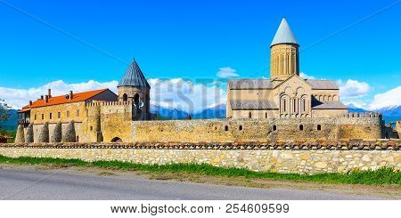 Panoramic Banner View Of Alaverdi Orthodox Monastery In Kakhetia Region In Georgia And Snow Peaks Of