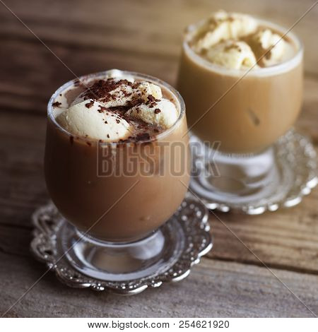 Latte Macchiato In A Glass With Cream On Wooden Background, Decorated Withcocoa Powder And Cinnamon,