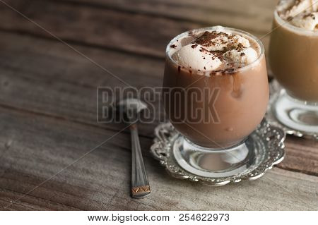 Latte Macchiato In A Glass With Cream On Wooden Background, Decorated Withcocoa Powder And Cinnamon,