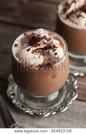 Latte Macchiato In A Glass With Cream On Wooden Background, Decorated Withcocoa Powder And Cinnamon,