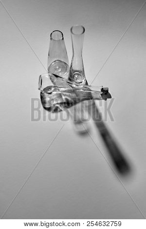Black and white photo of glass bottles on a gray background with shadows, place for text. Test glass flask in research laboratory. Laboratory concept.