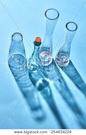 Glass transparent chemical laboratory glasses empty with shadows and reflection on the surface on a blue background, place for text. Laboratory concept.