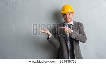 Young redhead man wearing architect outfit and helment very happy pointing with hand and finger
