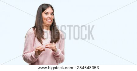 Young beautiful hispanic woman wearing a sweater disgusted expression, displeased and fearful doing disgust face because aversion reaction. With hands raised. Annoying concept.