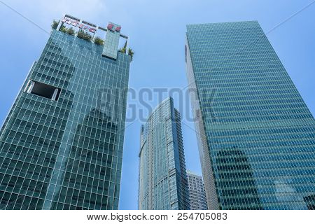 Singapore  - August 11, 2018: Green And Blue Skyscrapers Downtown With Blue Sky