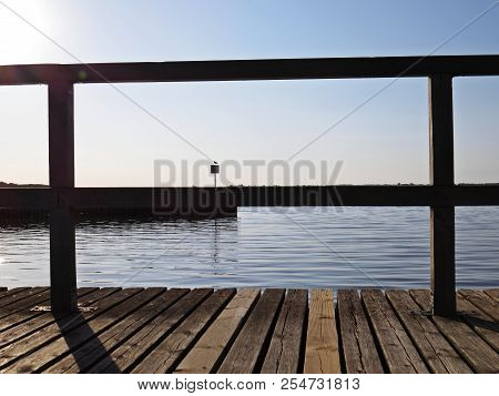 Wharf Catwalk During Sunset Over Beautiful Lake With Cloudy Sky In The Background