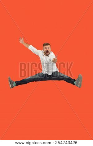 Freedom In Moving. Mid-air Shot Of Handsome Happy Young Man Jumping And Gesturing Against Orange Stu