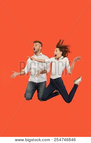 Freedom In Moving And Forward Motion. The Surprised Young Couple Jumping And Gesturing Against Red S