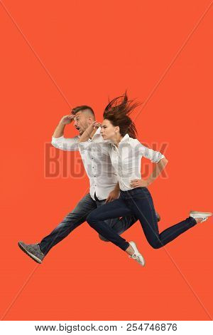 Freedom In Moving And Forward Motion. The Happy Young Couple Jumping And Gesturing Against Red Studi