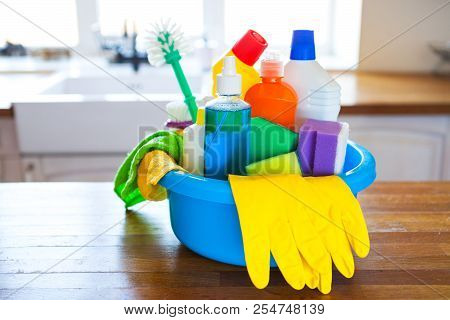 Basket With Cleaning Items On Blurry Background White Citchen. Cleaning Concept.