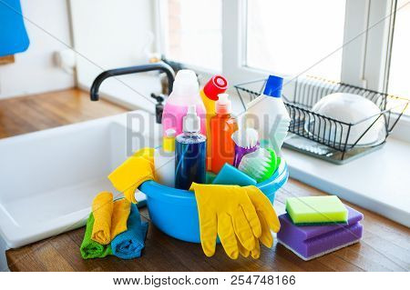 Basket With Cleaning Items On Blurry Background White Citchen. Cleaning Concept.