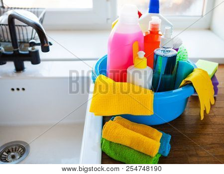 Basket With Cleaning Items On Blurry Background White Citchen. Cleaning Concept.
