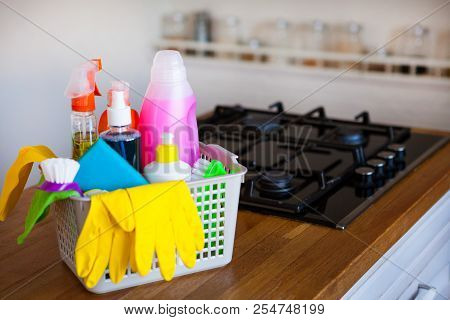 Basket With Cleaning Items On Blurry Background White Citchen. Cleaning Concept.