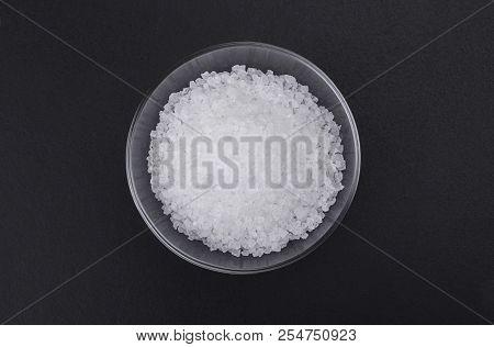 Natural Sea Iodized Salt In A Small Glass Bowl Isolated On A Black Background, Top View