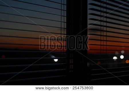 Through The Open Blinds You Can See The Evening Sunset.
