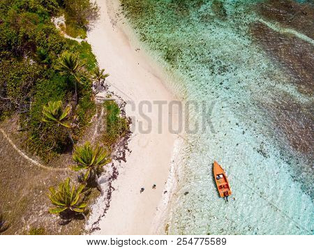 Aerial drone view of Petit Tabac tropical island, turquoise Caribbean sea of Tobago cays, and a family with kids in St Vincent and Grenadines