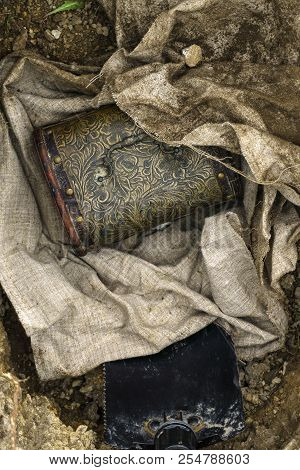 Vintage Chest Deployed From A Tissue Bundle Excavated From The Ground, And Trenching Tool In Pit
