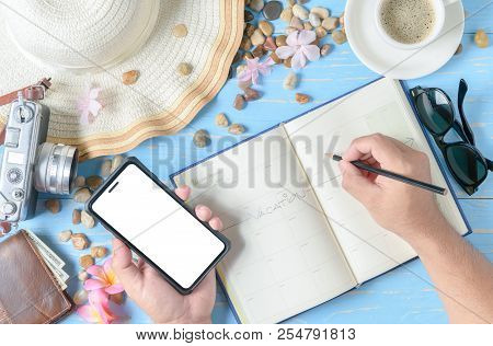 Man Writing On Planner Book And Hold Mobile Phone