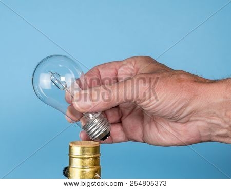 Senior Caucasian Man Unscrewing A Halogen Lightbulb As Concept For Eu Decision To Ban The Light Bulb