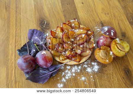 Fresh Plum Tartlet With Powdered Sugar And Plum On A Wooden Board. The View From The Top.