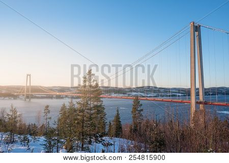 View At Hoga Kusten Bridge In Winter In Sweden. Hoga Kusten Suspension Bridge In Sweden.