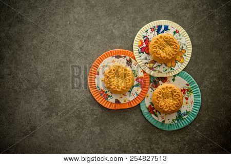 Traditional moon cakes is eaten during the Mid-Autumn Festival. Flatlay on table, top down view low light with copy space. The Chinese character on the mooncake represent 