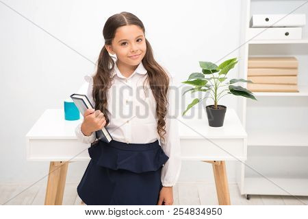 Excellent First Former. Girl Child Hold Book While Stand Table White Interior. Schoolgirl Studying T