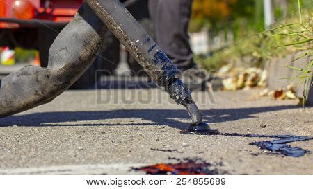 Workers Repair The Road, Pour Small Cracks With Bitumen To Prevent Further Destruction Of The Road S