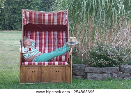 With The Stetson As A Sunscreen For Her Feet, A Red Drink And Suncream So The Attractive Woman Enjoy