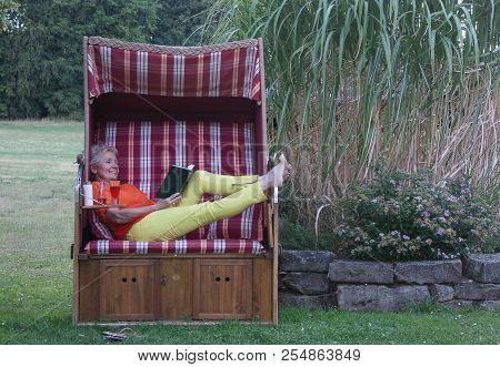 The New Book, A Cool Drink And The Sunscreen Are All Part Of A Relaxing Day In The Roofed Wicker Bea