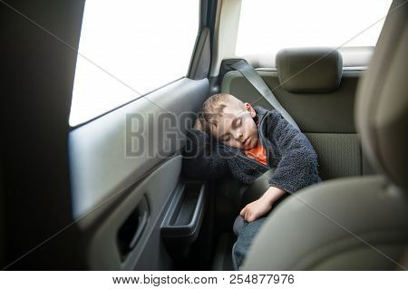 Cute Little Caucasian Kid Wearing Warm Clothes Sleeping In Inside Car Wearing Seat Belt