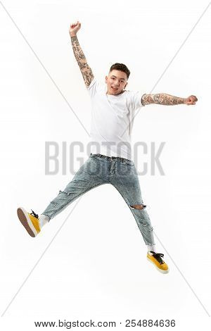 Freedom In Moving. Mid-air Shot Of Handsome Happy Young Man Jumping And Gesturing Against White Stud