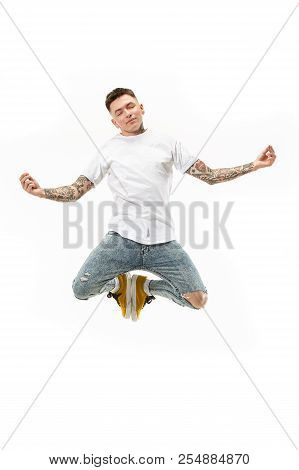 Yoga In Moving. Mid-air Shot Of Handsome Happy Young Man Jumping And Posing In Asana Against White S