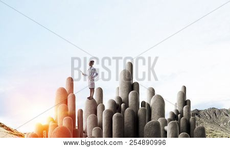 Young Female Doctor With Folder In Hands Satnding On Stone Column